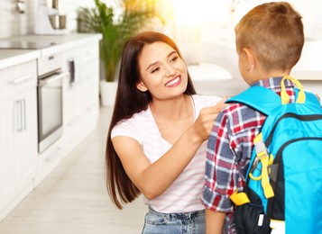 Image of Happy mother and little child with backpack ready for school in kitchen