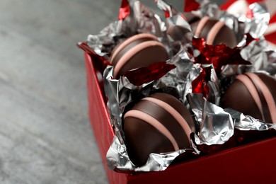 Gift box with delicious chocolate truffles on grey table, closeup. Space for text