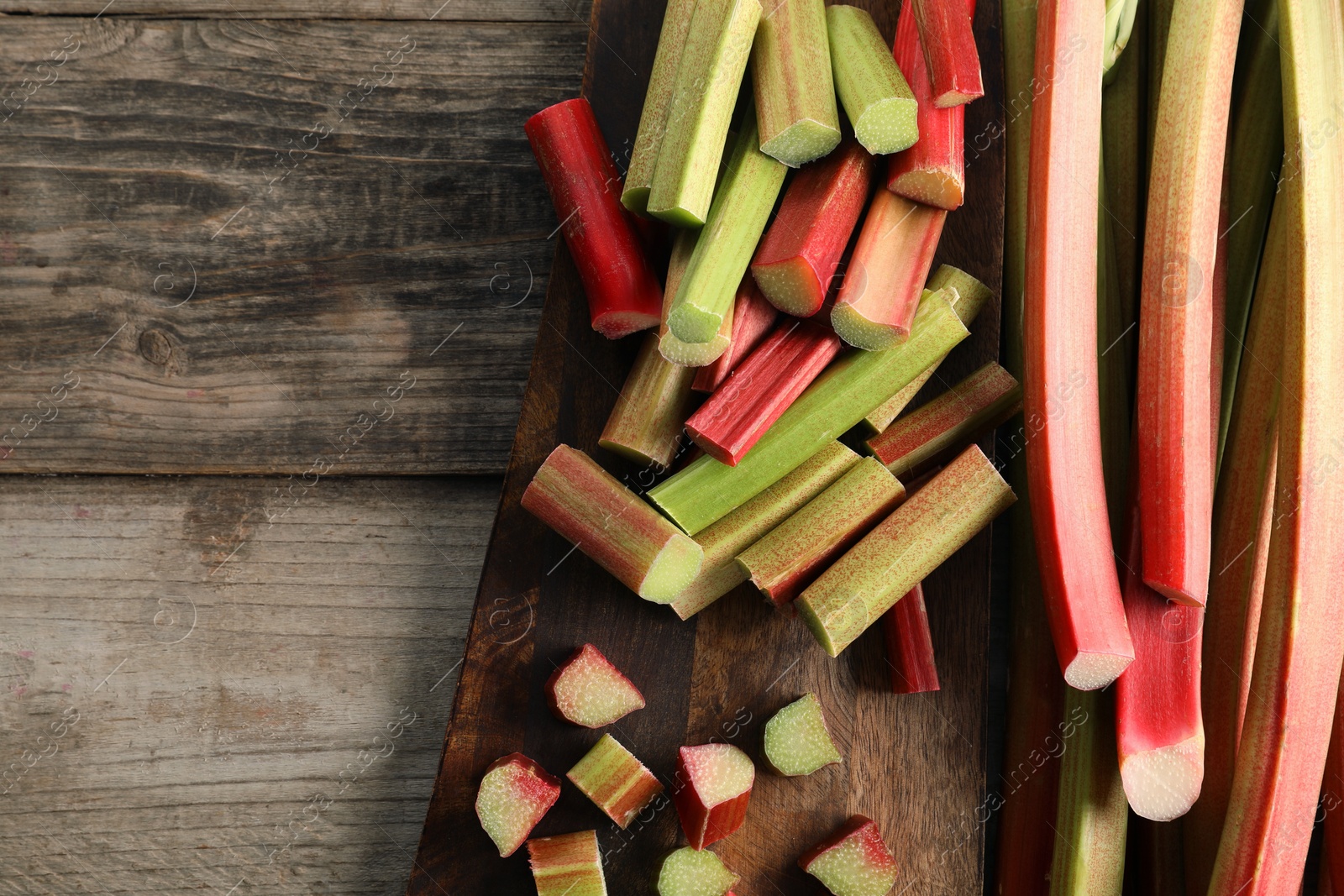 Photo of Many cut rhubarb stalks on wooden table, top view. Space for text