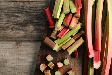 Photo of Many cut rhubarb stalks on wooden table, top view. Space for text