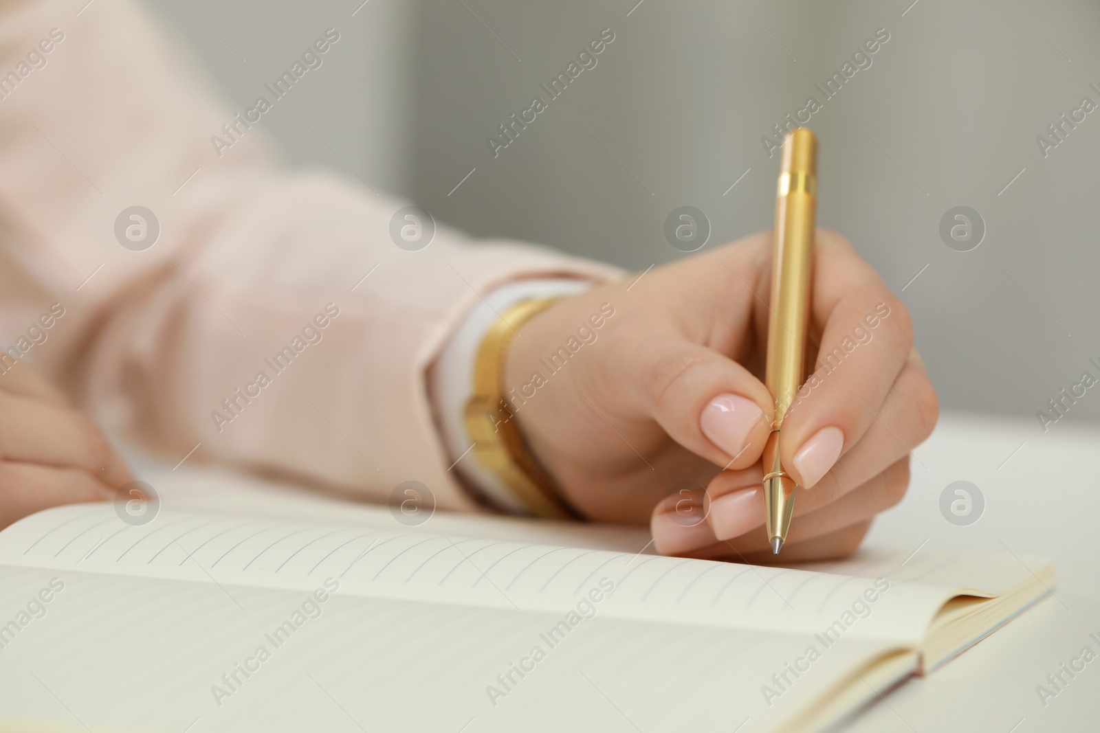 Photo of Woman writing in notebook at white table, closeup