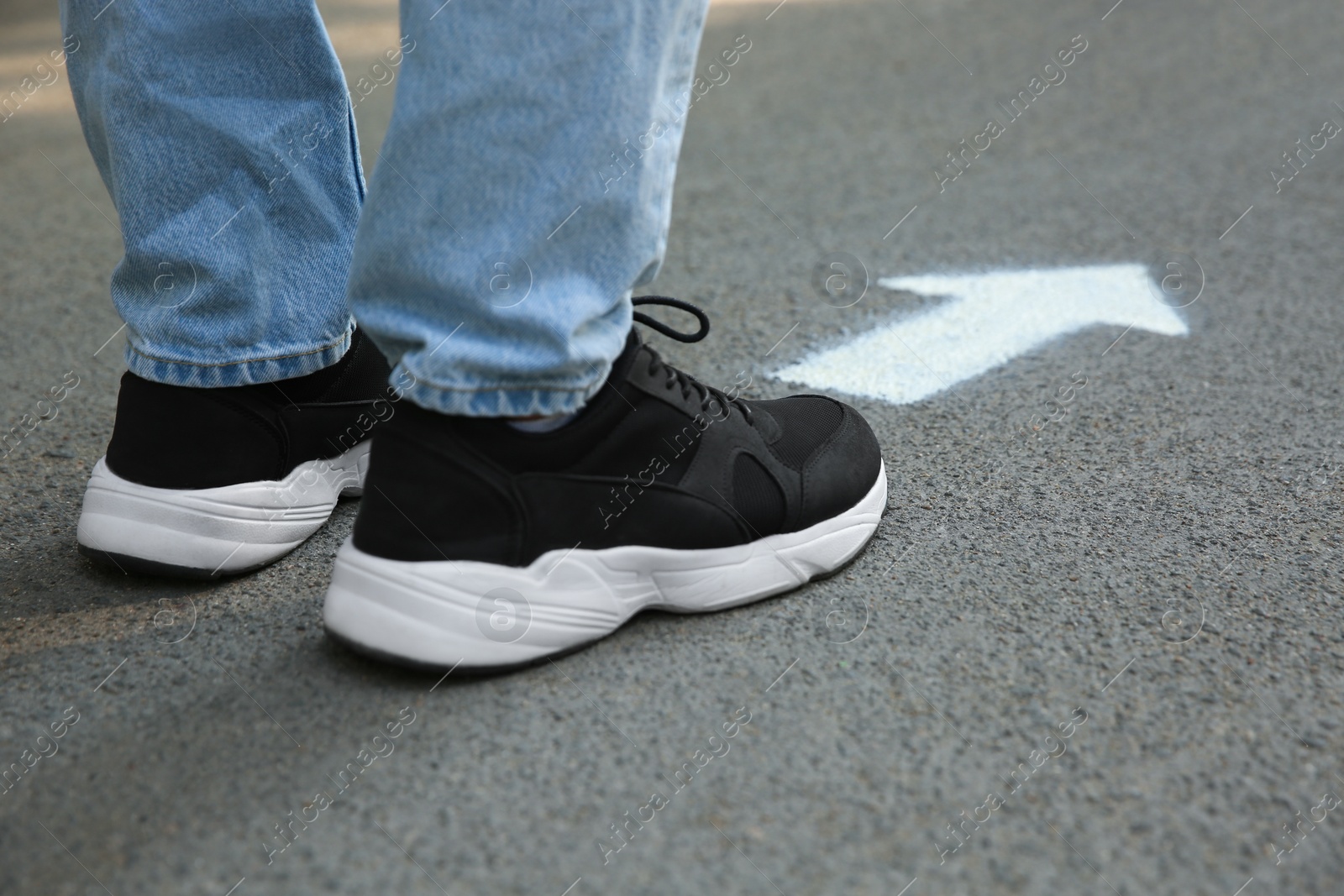 Photo of Man standing near arrow on asphalt, closeup