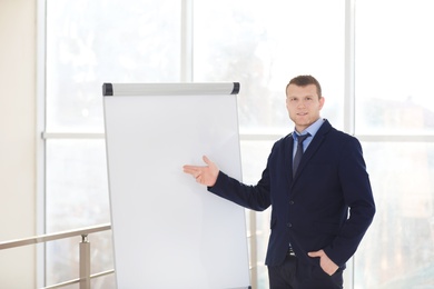 Business trainer giving presentation on flip chart board indoors