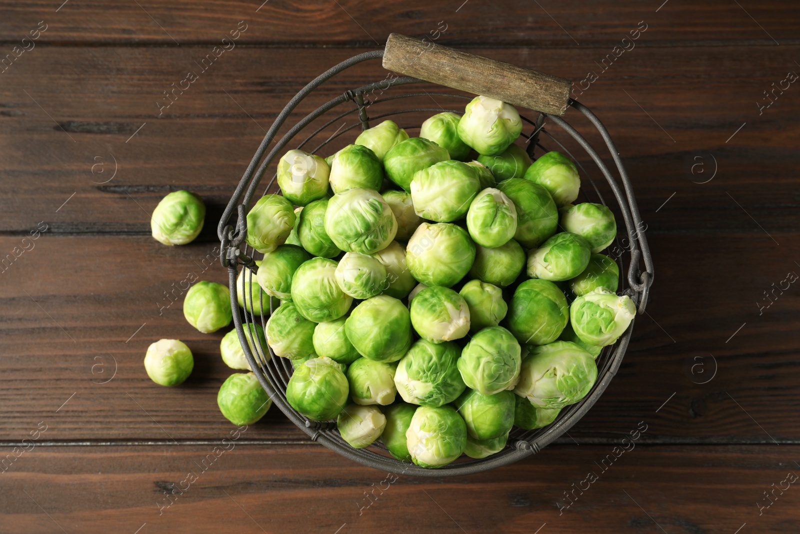 Photo of Metal basket with fresh Brussels sprouts on wooden background, top view