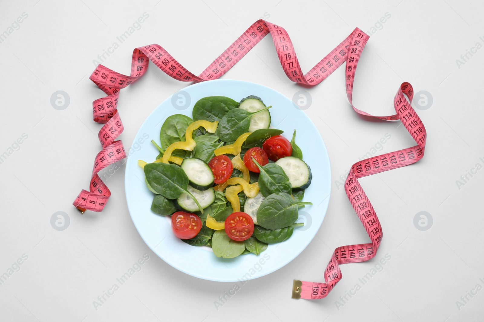 Photo of Measuring tape and salad on light background, flat lay