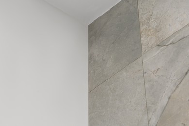 Wall with beautiful light gray marble tiles indoors, low angle view