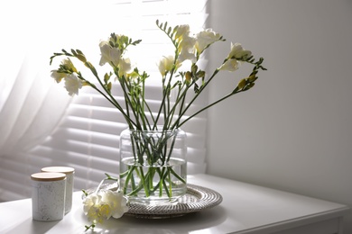 Photo of Beautiful spring freesia flowers on table in room