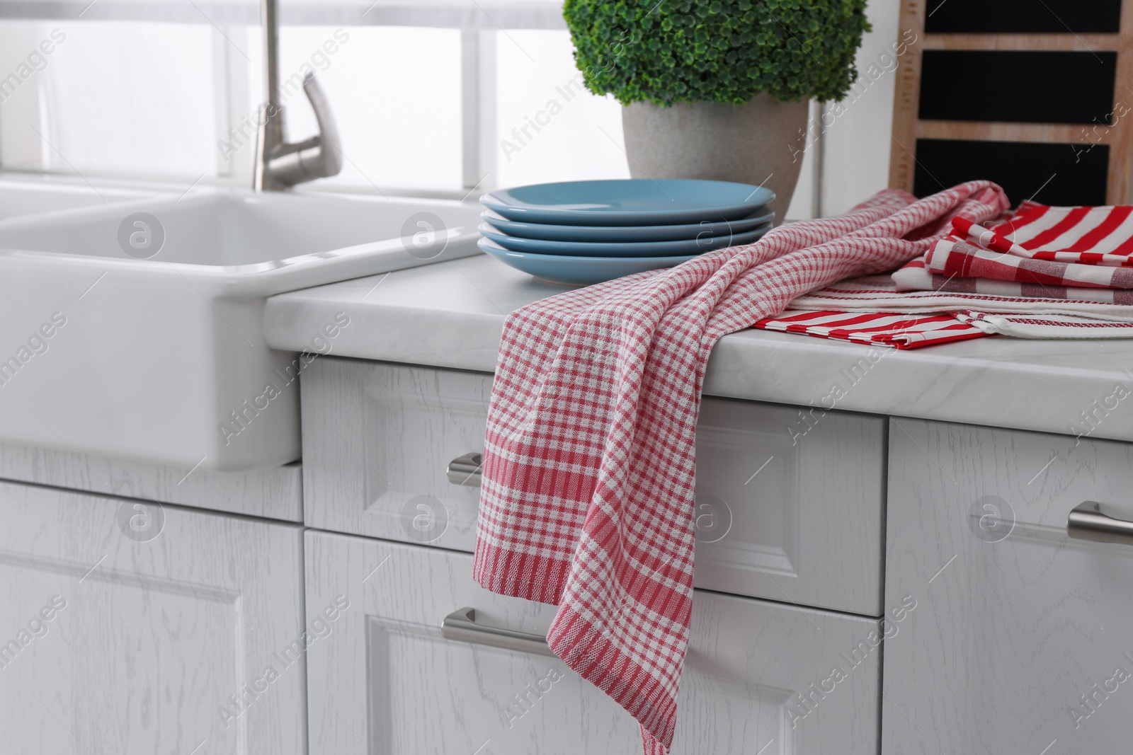 Photo of Different towels and stack of plates near sink on kitchen counter