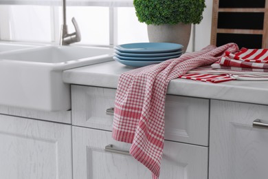 Different towels and stack of plates near sink on kitchen counter