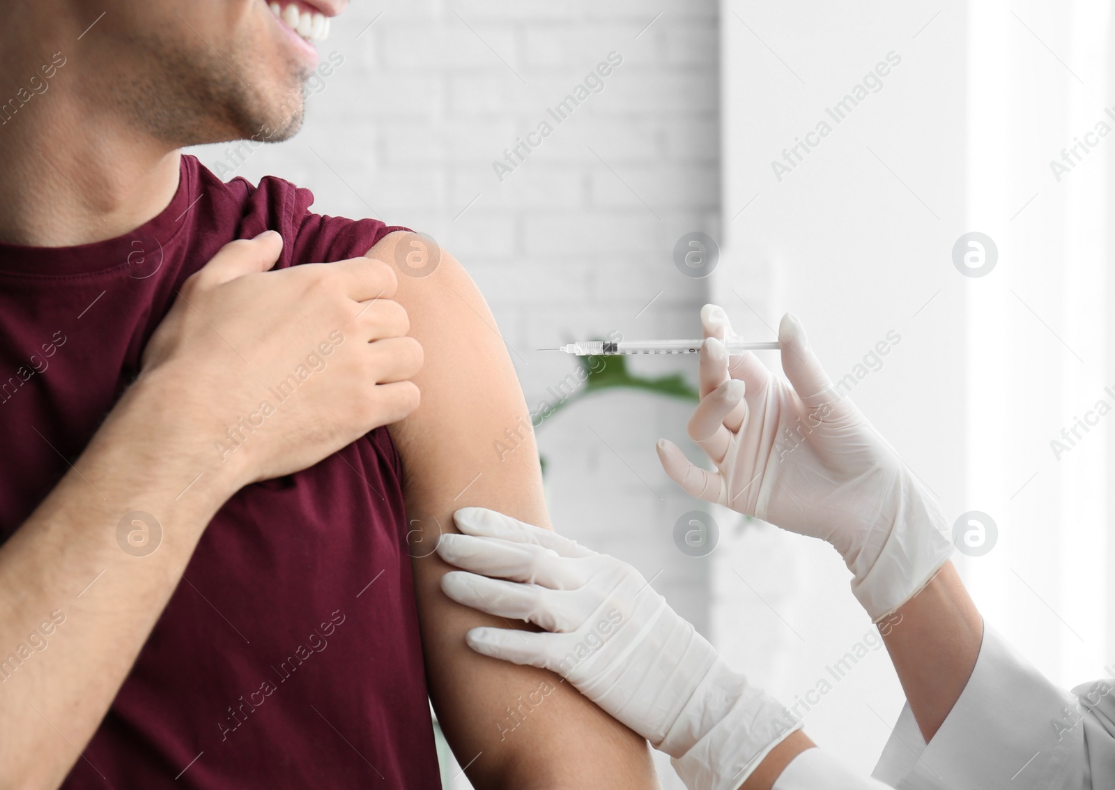 Photo of Doctor vaccinating male patient in clinic