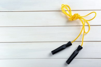 Photo of Skipping rope on white wooden table, top view. Space for text