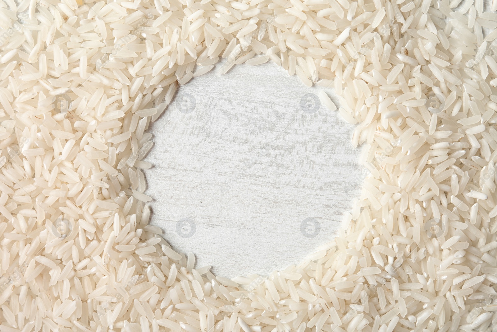 Photo of Round frame made with long grain rice on white background, top view. Space for text