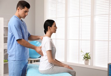 Orthopedist examining young woman's back in clinic, space for text. Scoliosis treatment