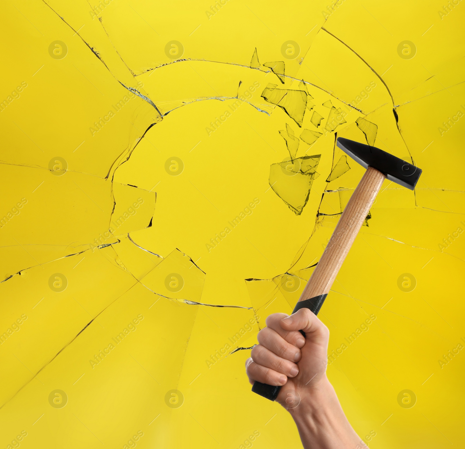 Image of Man with hammer breaking up glass against yellow background. closeup 