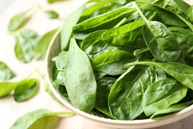 Photo of Bowl of fresh green healthy spinach on table, closeup