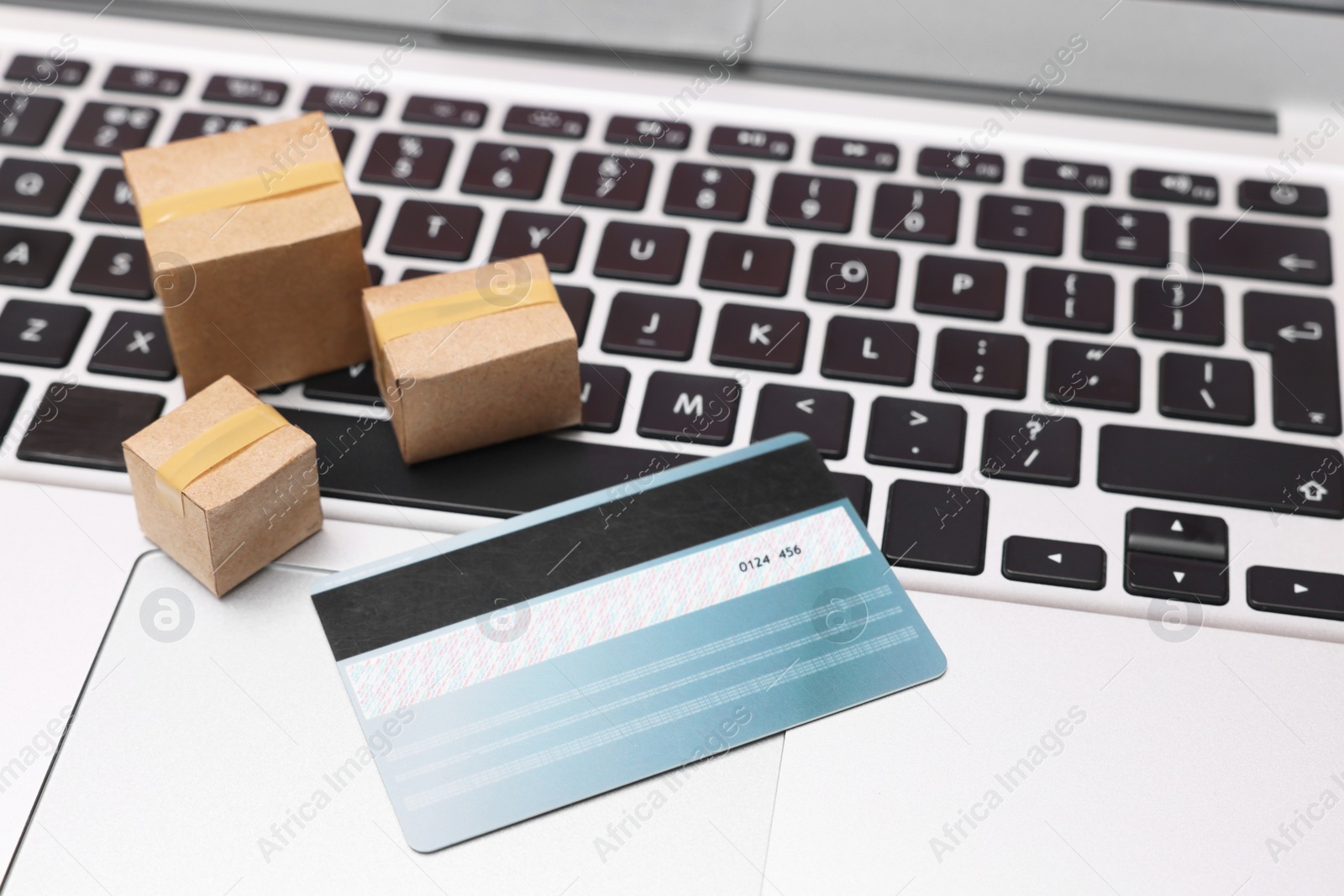 Photo of Internet shopping. Small cardboard boxes and credit card on laptop, closeup