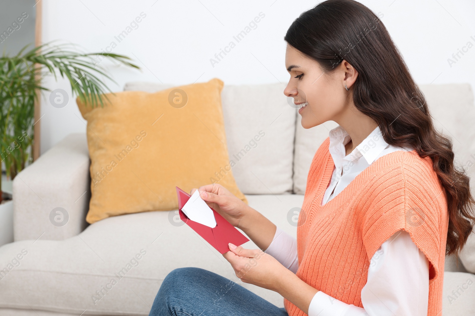 Photo of Young woman with greeting card in living room, space for text