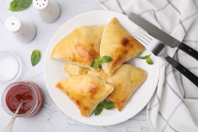 Photo of Delicious samosas served on white textured table, flat lay