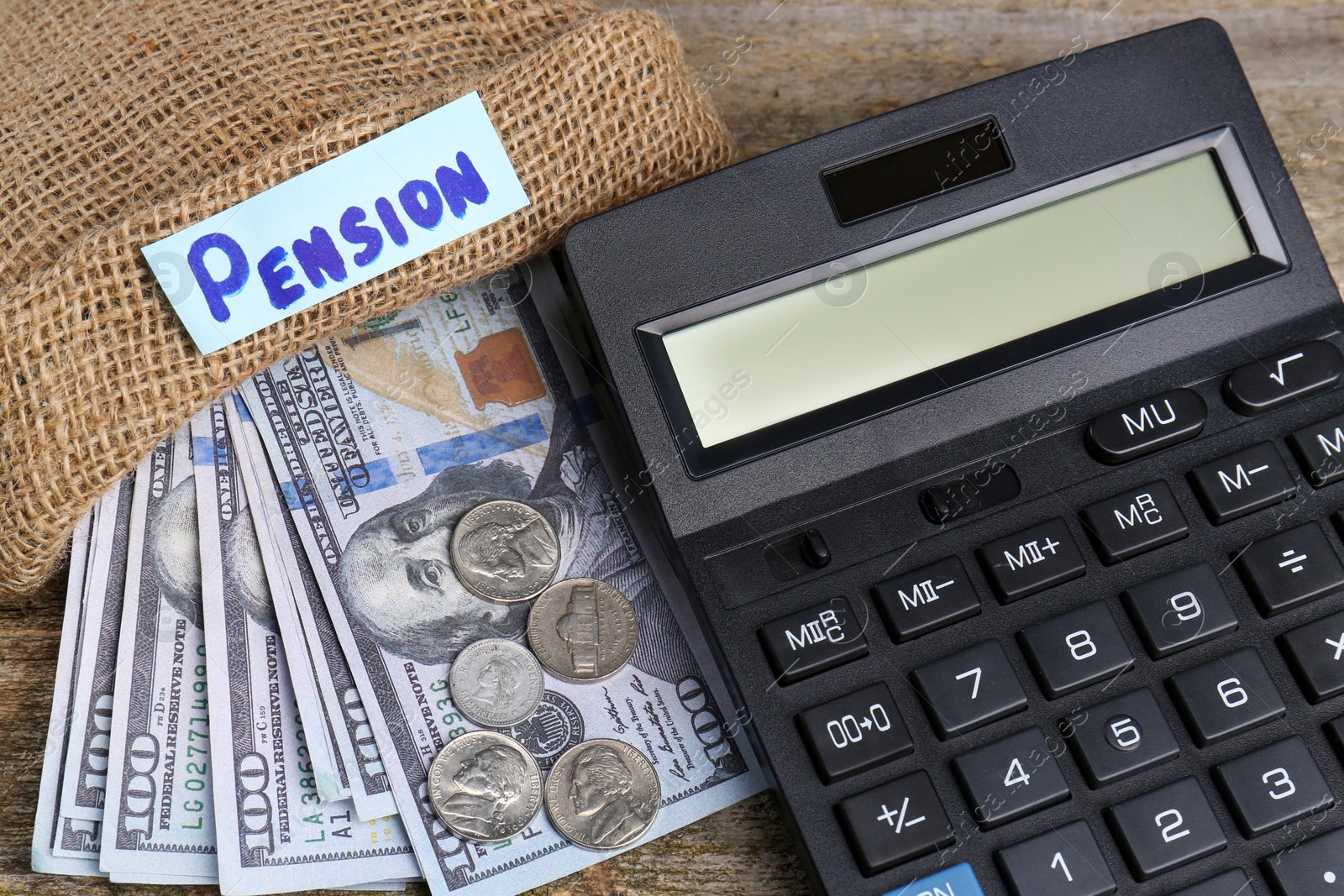 Photo of Bag with money, word Pension and calculator on wooden table, closeup. Retirement concept