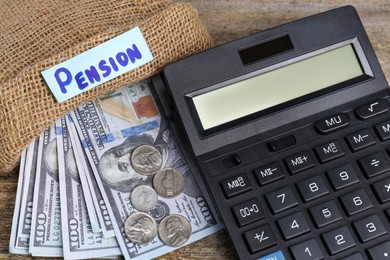 Photo of Bag with money, word Pension and calculator on wooden table, closeup. Retirement concept
