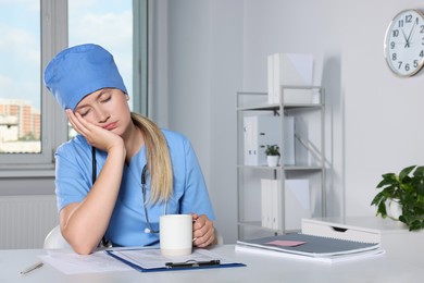 Tired young doctor sleeping at workplace in office