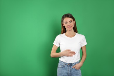 Photo of Healthy woman holding hand on belly against green background. Space for text