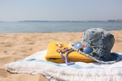 Photo of Denim hat and beach accessories on sand near sea. Space for text