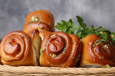 Photo of Delicious pampushky (buns with garlic) in wicker basket, closeup