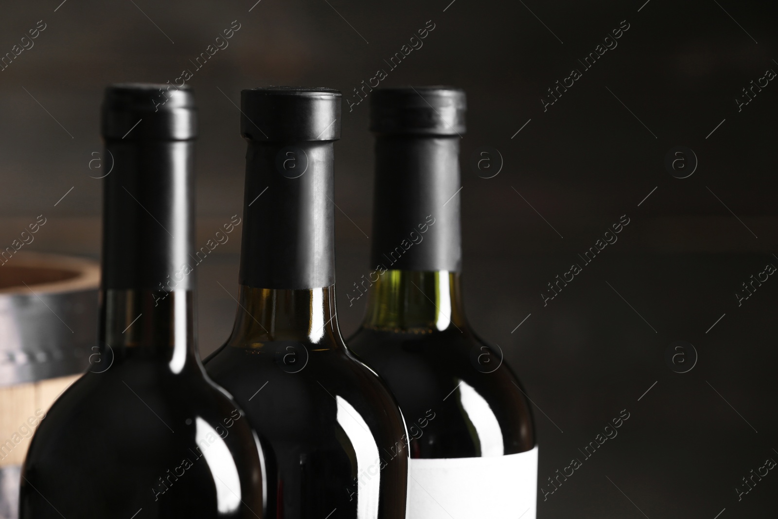 Photo of Bottles of wine on dark background, closeup. Space for text