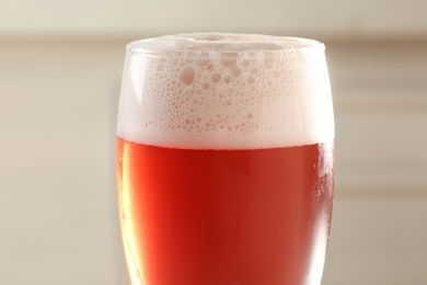 Photo of Glass of red tasty beer with foam, closeup