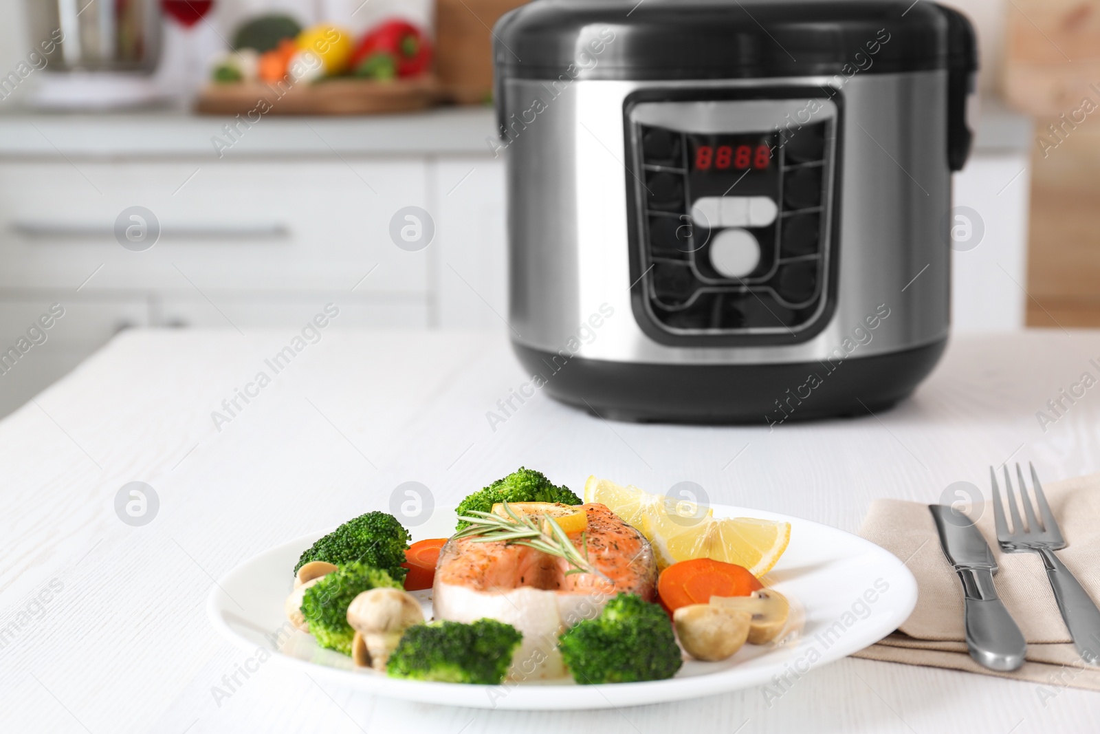 Photo of Plate with salmon steak and garnish prepared in multi cooker on table