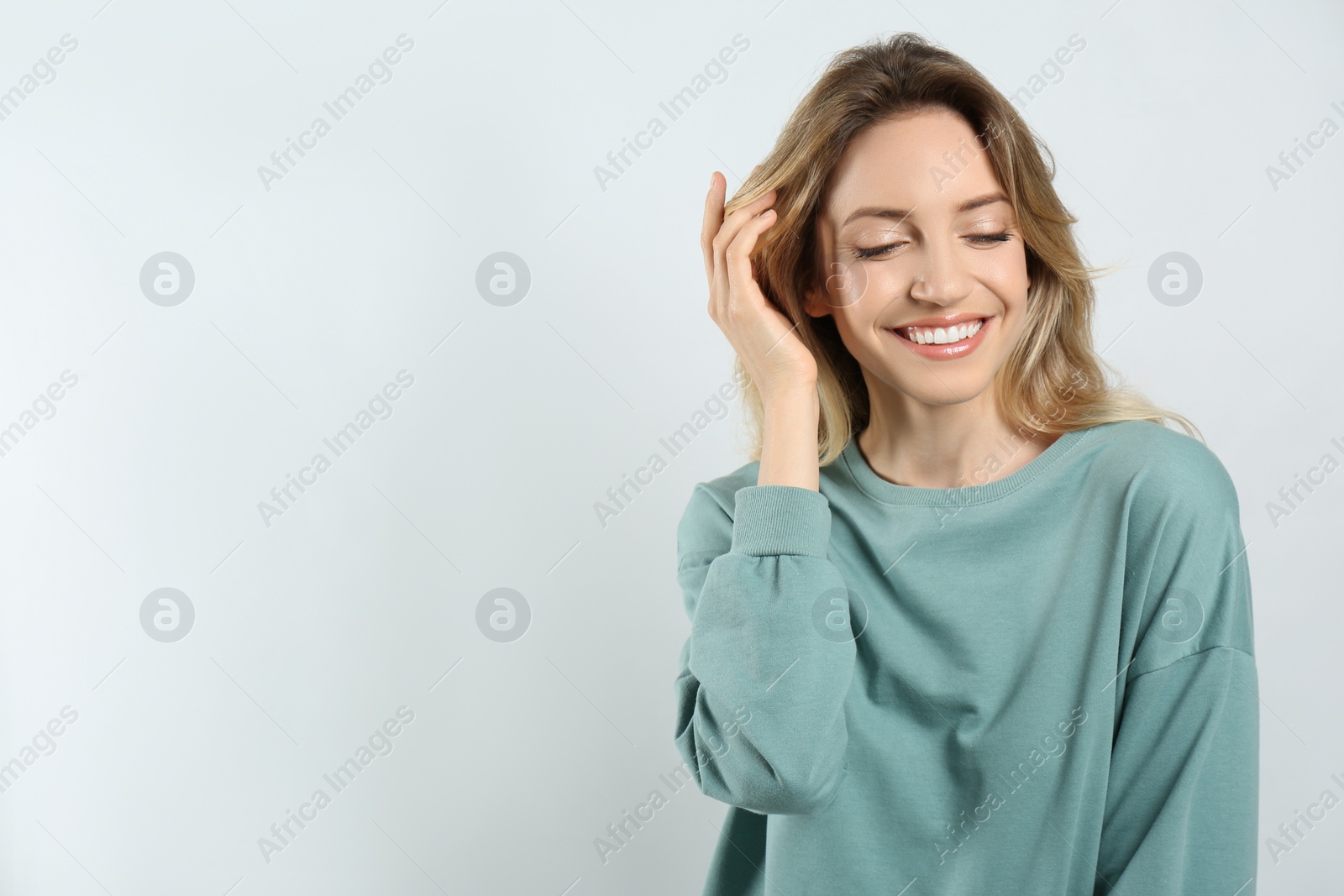 Photo of Portrait of happy young woman with beautiful blonde hair and charming smile on light background. Space for text