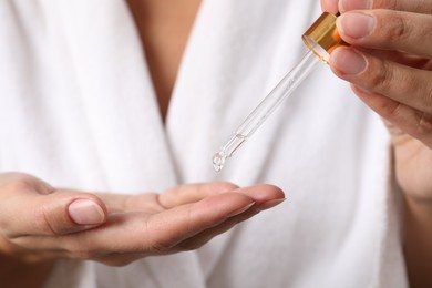 Photo of Woman applying cosmetic serum onto her hand, closeup