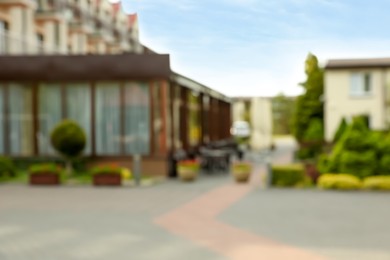 Photo of Blurred view of city street with buildings and beautiful green plants