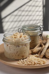 Photo of Platter with tasty prepared horseradish and roots on white wooden table