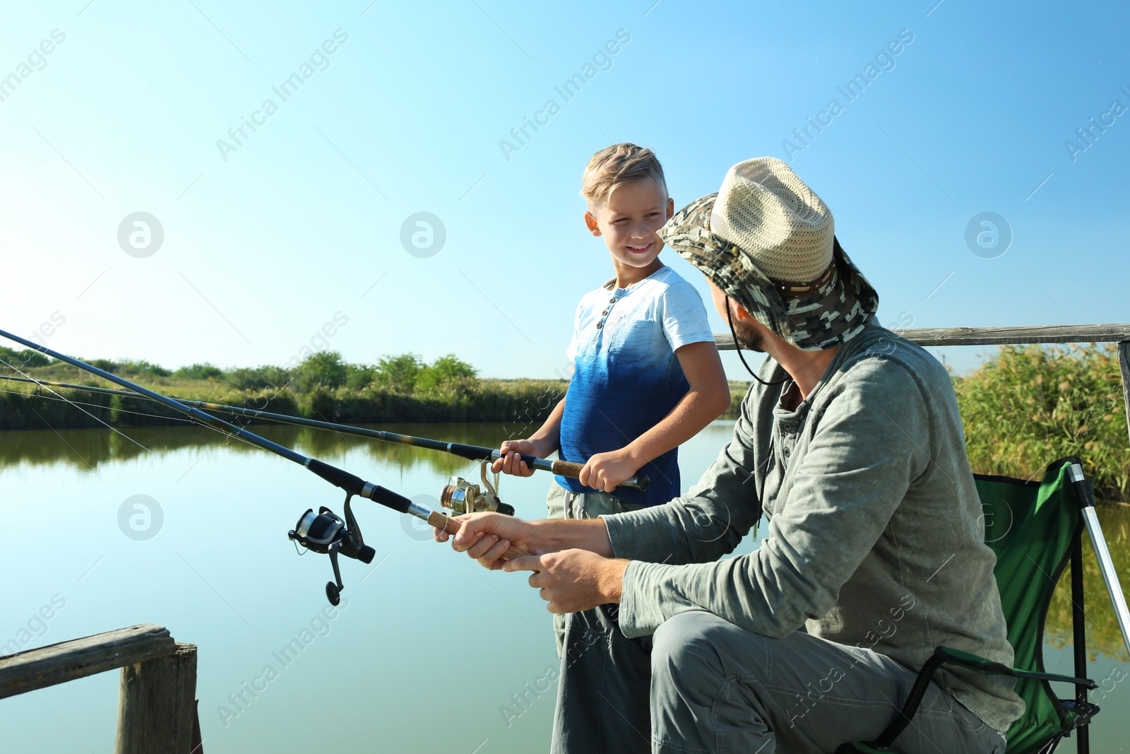 Photo of Father and son fishing together on sunny day