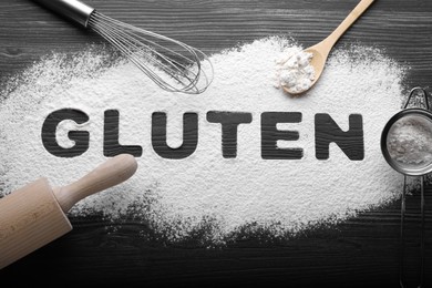 Photo of Word Gluten written with flour and different kitchen utensils on dark wooden table, flat lay