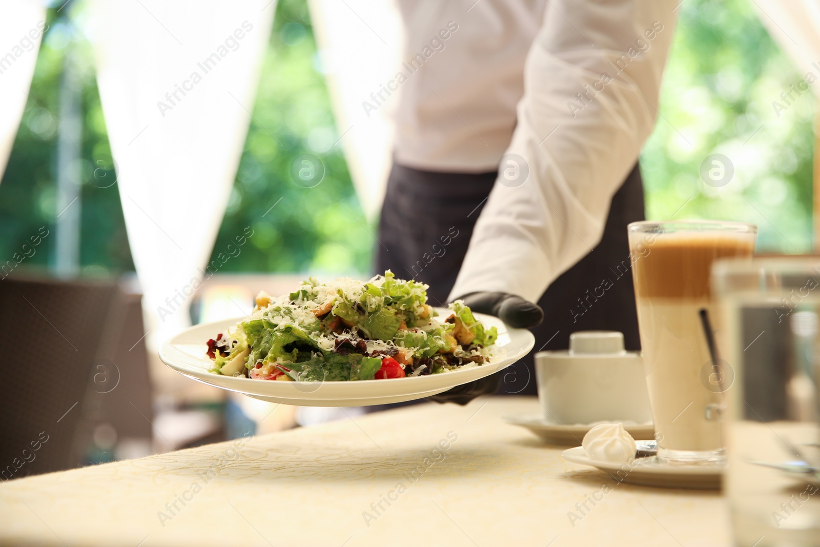 Photo of Waiter serving salad in restaurant, closeup. Catering during coronavirus quarantine