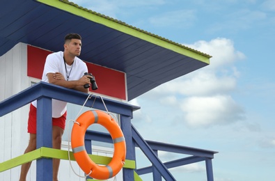 Photo of Male lifeguard with binocular on watch tower