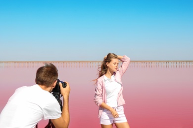 Photo of Professional photographer taking photo of woman near pink lake on sunny day