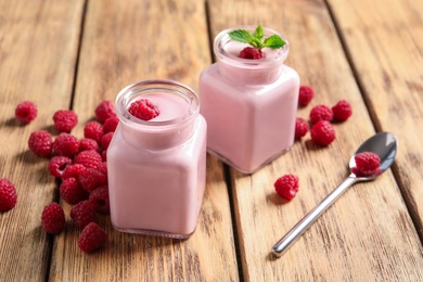 Photo of Glass jars of tasty smoothie with raspberries on wooden table