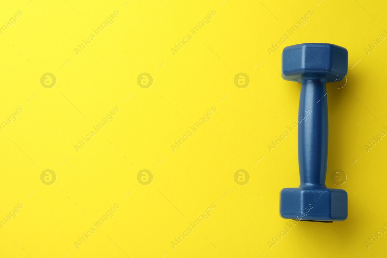 Photo of Stylish dumbbell on yellow background, top view. Space for text