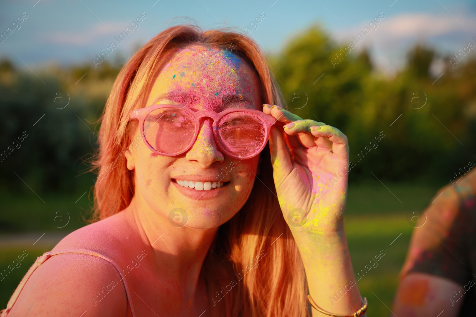 Photo of Happy woman covered with colorful powder dyes outdoors. Holi festival celebration