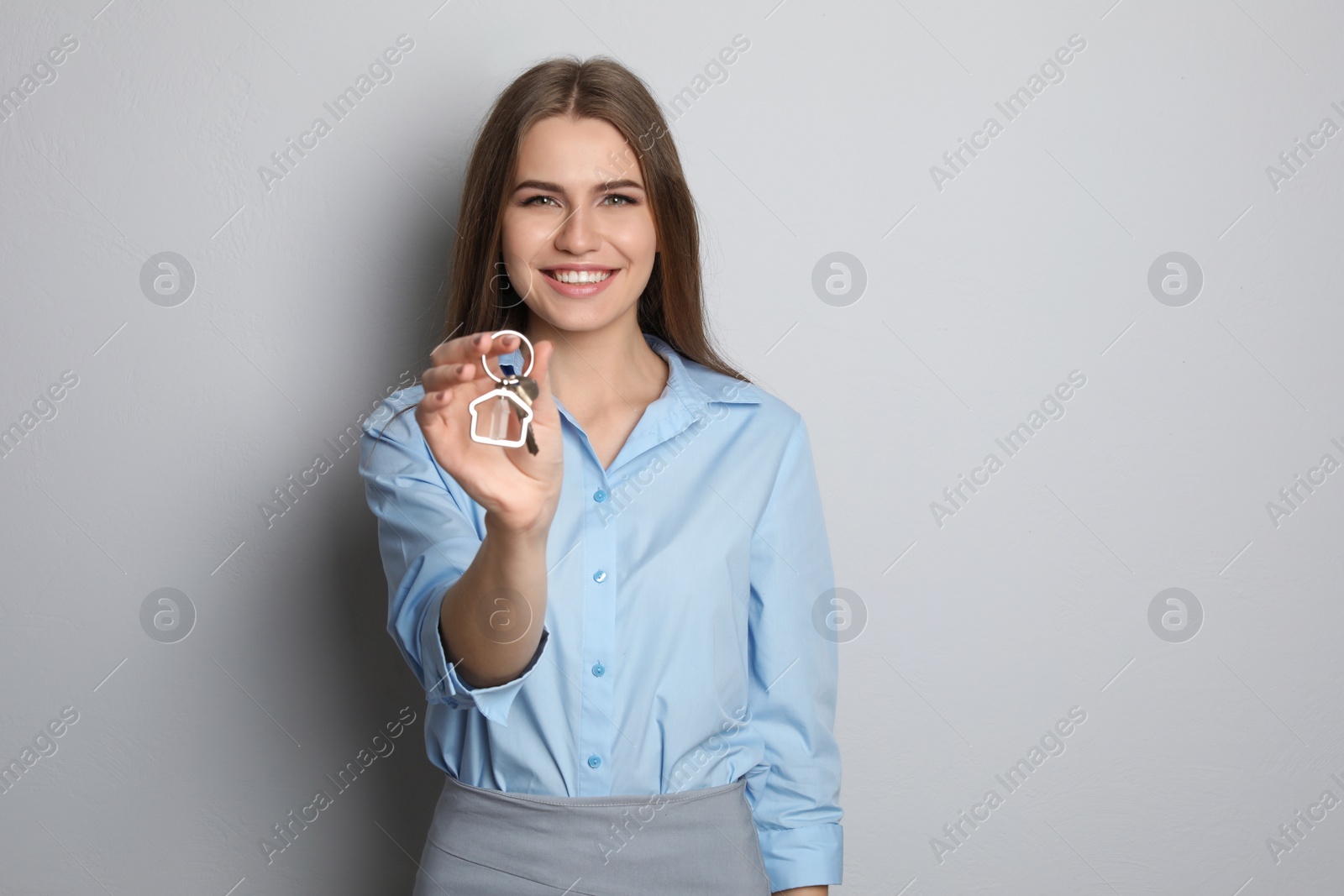 Photo of Beautiful real estate agent with key on grey background