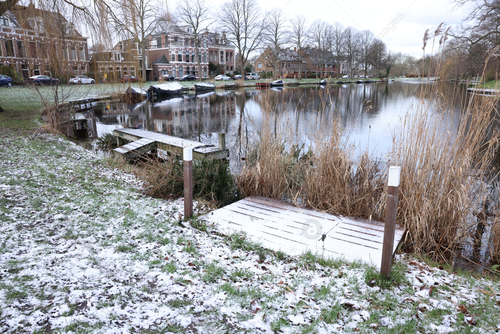 Photo of Picturesque view of water canal with moored boats in city on winter day