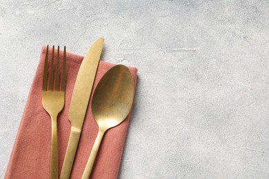 Photo of Stylish cutlery and napkin on light grey table, top view. Space for text