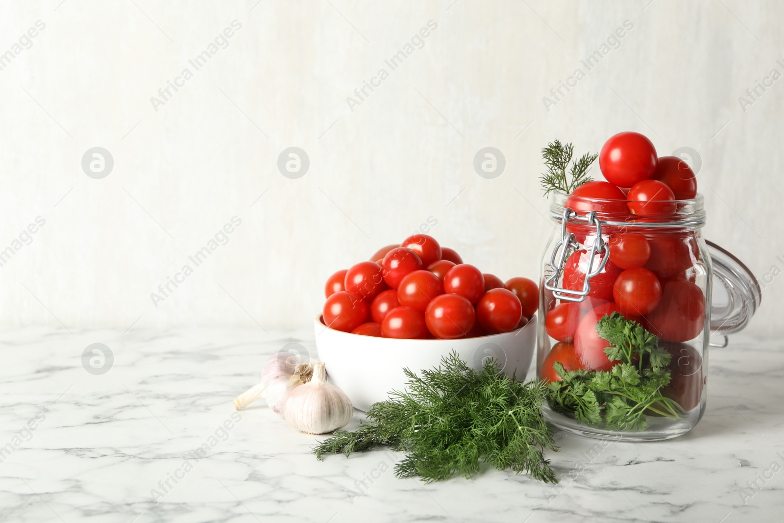 Photo of Pickling jar with fresh ripe cherry tomatoes on white marble table. Space for text