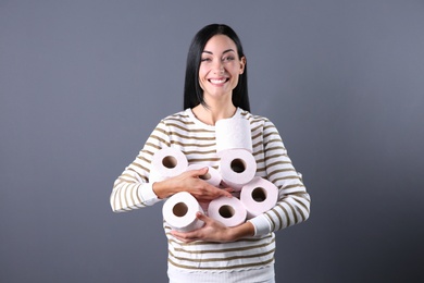 Beautiful woman holding toilet paper rolls on color background