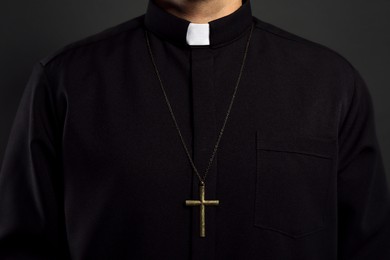 Photo of Priest with cross on black background, closeup