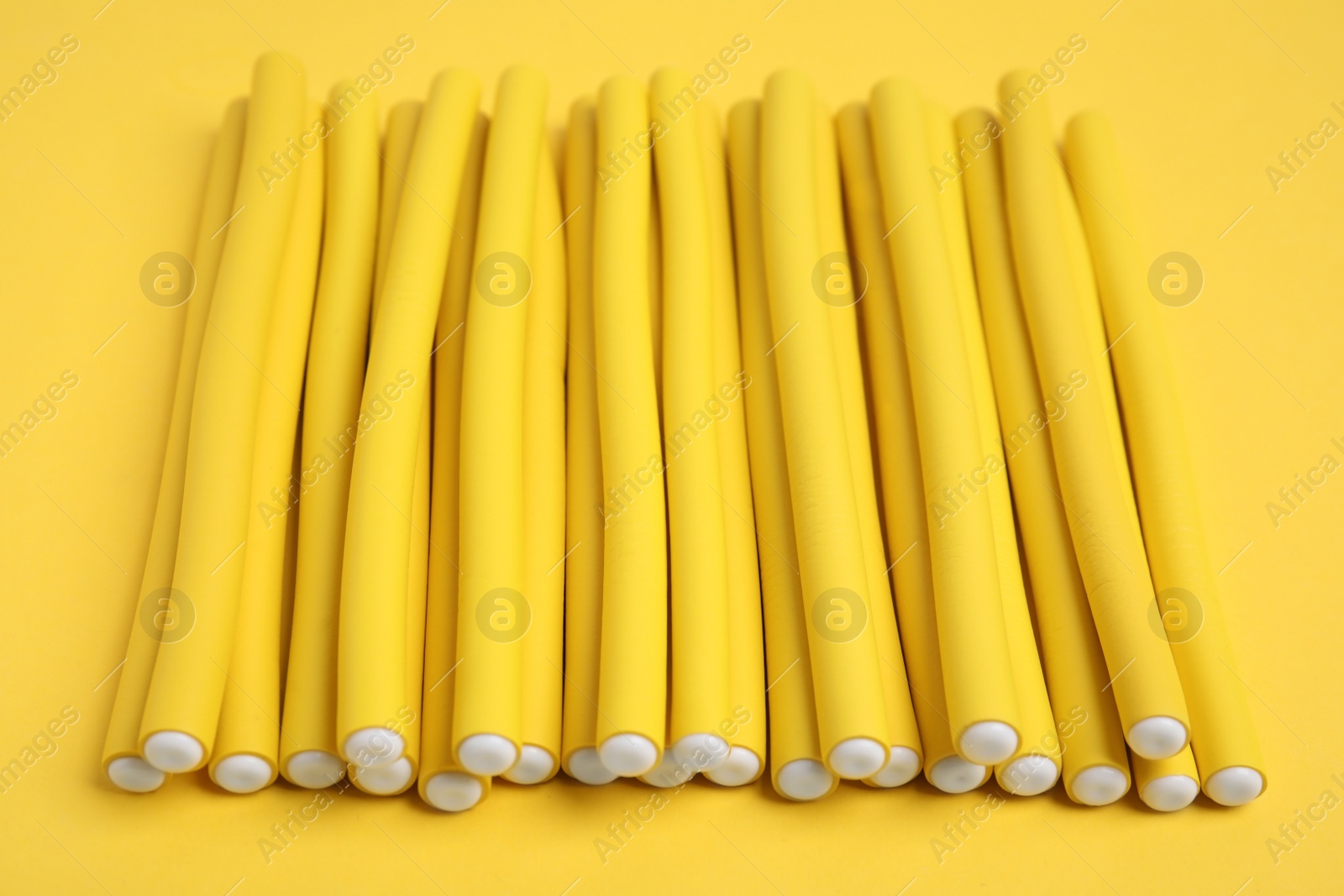 Photo of Curling rods on yellow background. Hair styling tool